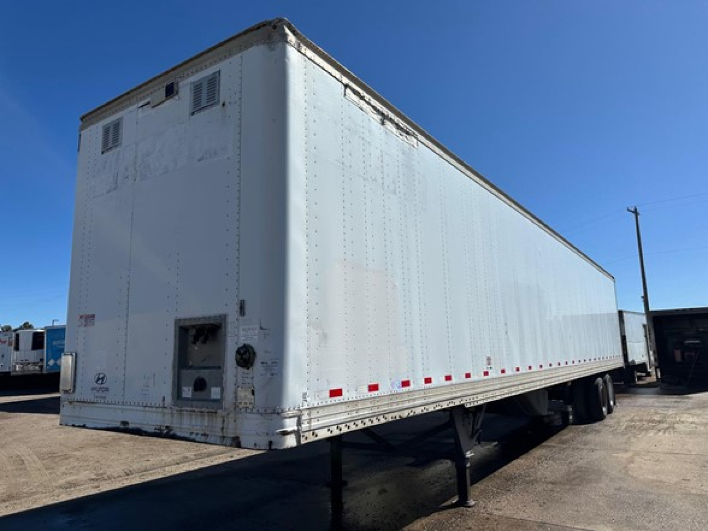 Trailer side view of a white 2015 Hyundai air ride dry van with riveted panels and double rear doors, storage and support legs visible.
