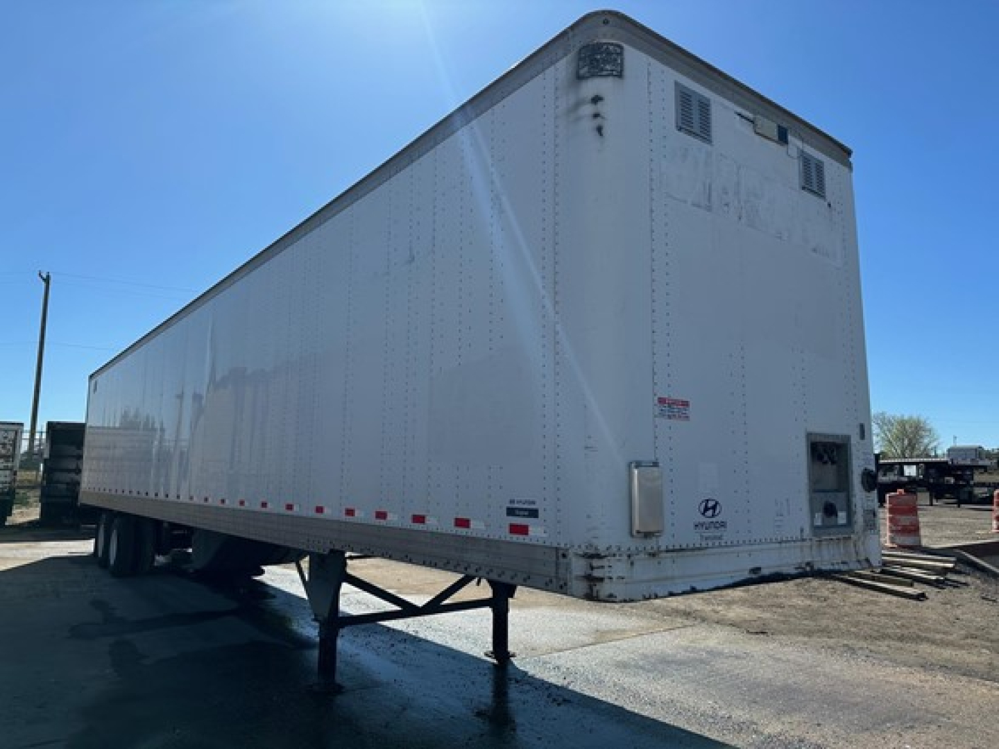 Hyundai air ride dry van trailer with white exterior, viewed from rear-left side, showing a raised landing gear, rear doors, and underride clearance