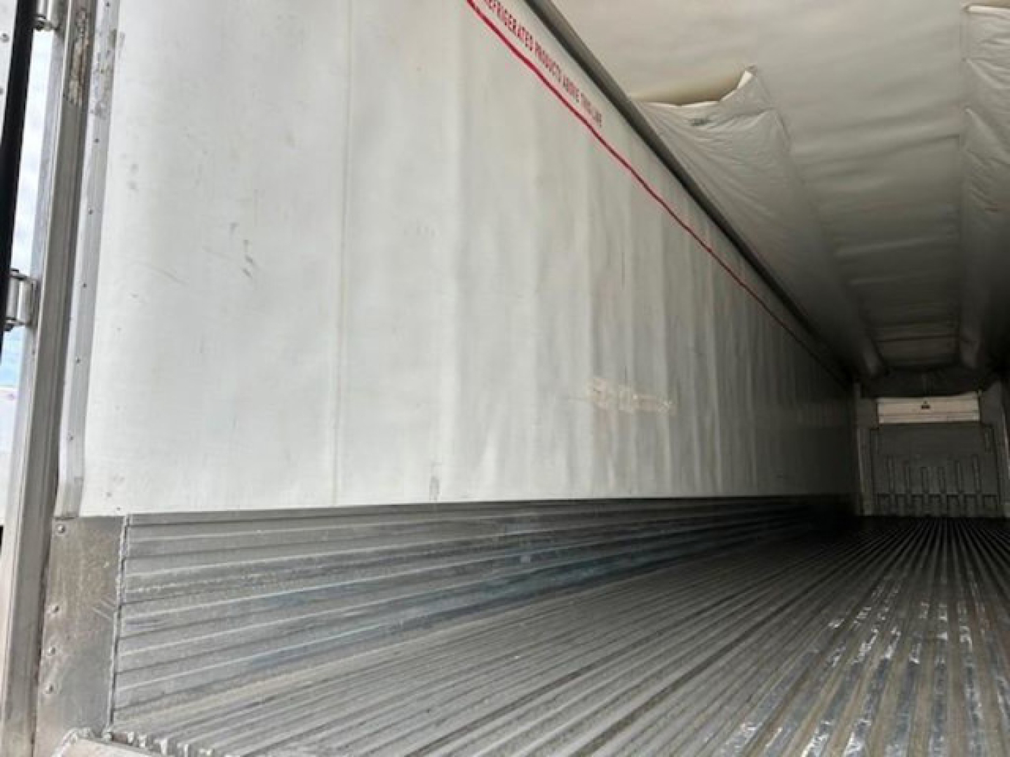 Refrigerated trailer interior with metal ribbed floor and insulated walls, seen from the side doorway in a 2019 Utility Reefer.