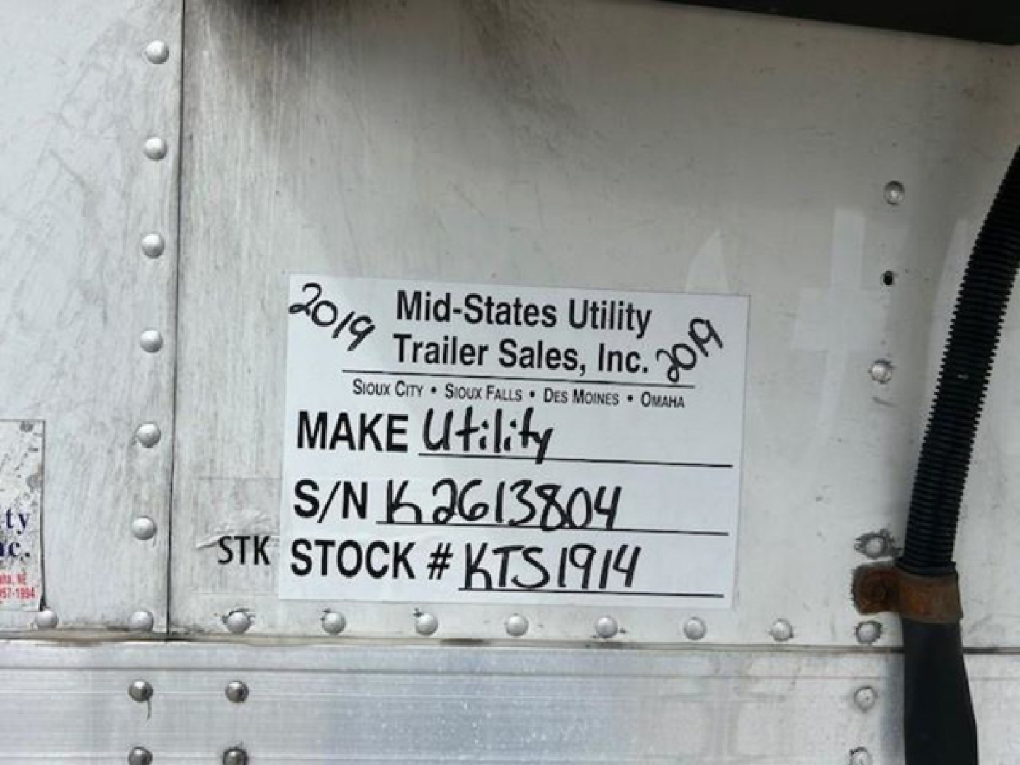 Trailer side with label reading ‘Mid-States Utility Trailer Sales, Inc.’, S/N K3613804, STOCK # KTS1914, 2019, MAKE Utility, on a refrigerated trailer.