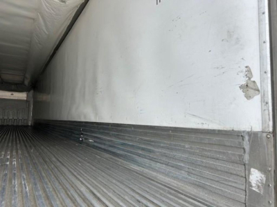 Trailer interior cargo area showing corrugated metal floor and side wall of a refrigerated trailer with light wear.