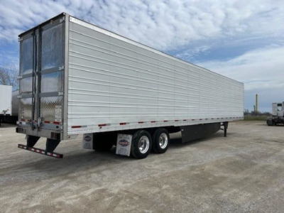 Utility refrigerated trailer viewed from side-rear showing tandem axles and metal exterior with doors at back.