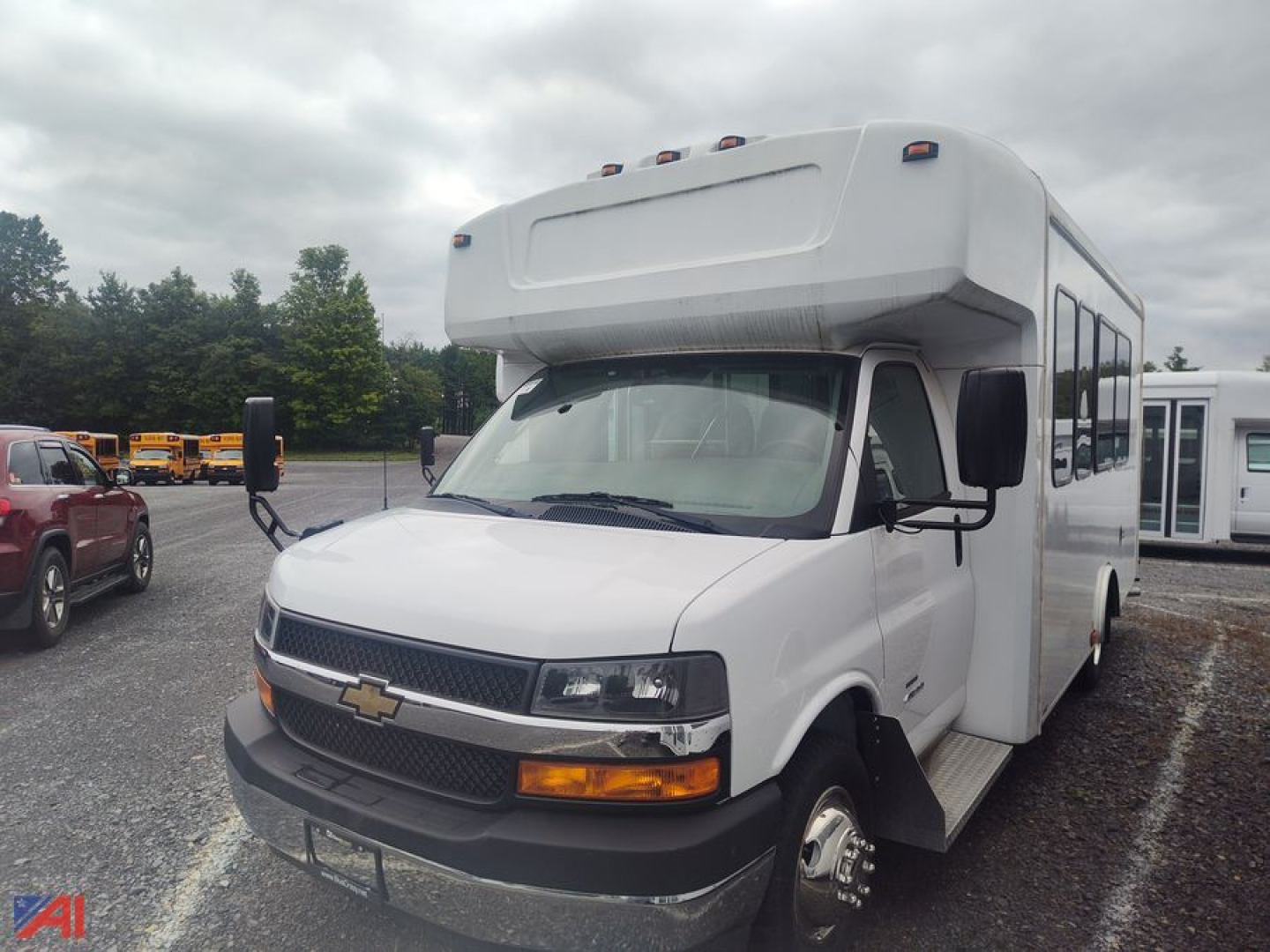 Bus front/side view showing Chevrolet Express G4500 bus body with cab-over styling, white exterior, black grille, amber turn signals, and side mirrors.