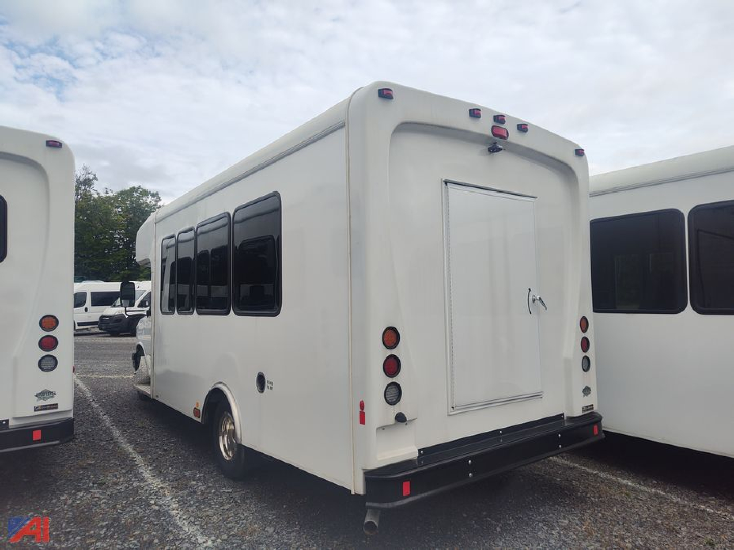 Bus rear view showing Chevrolet Express G4500 body with rear doors and taillights in a parking lot.