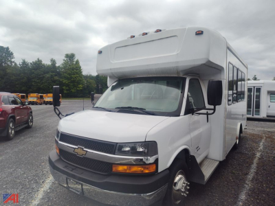 Bus front/side view showing Chevrolet Express G4500 bus body with cab-over styling, white exterior, black grille, amber turn signals, and side mirrors.