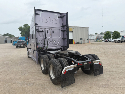 Conventional sleeper truck rear view showing third-axle configuration and purple cab; Freightliner Cascadia 126 chassis with dual rear axles and mud flaps.