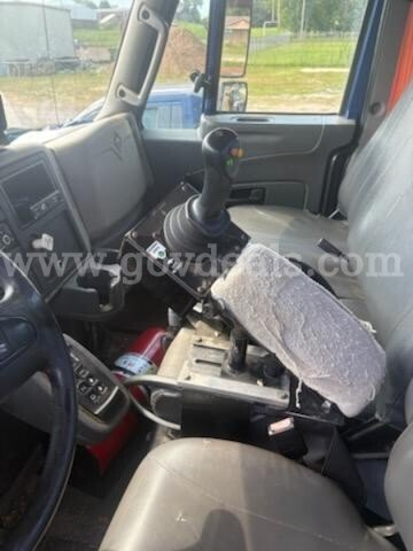 Cab interior of a 2011 International 7500 medium-duty truck showing gear shifter, steering wheel, and driver seat with a worn seat cover.