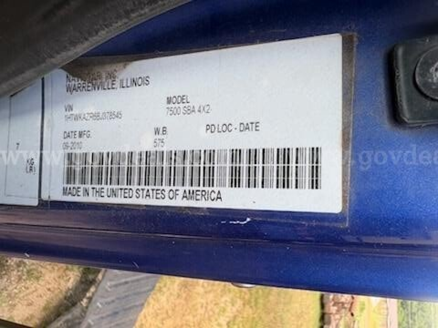 Label on a blue truck door jamb showing VIN, stock number, model, location, and barcode. Text includes 'WARRENVILLE ILLINOIS', 'MODEL 7500 SBAA 4X2', 'VIN 1HTWKAZR6BJ378545', 'DATE MFG', 'W.B. 575', 'MADE IN THE UNITED STATES OF AMERICA'.