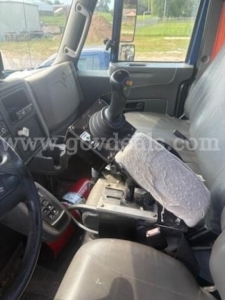 Cab interior of a 2011 International 7500 medium-duty truck showing gear shifter, steering wheel, and driver seat with a worn seat cover.