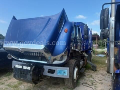 Truck cab with blue hood raised showing front bumper and side mirror; license plate area and blue state tag; visible text includes 12-digit license-like tags and website watermark; no clear engine text visible.