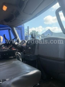 Interior of a 2011 International 7500 cab showing driver seat area and dashboard with controls, windshield, and passenger side panel.