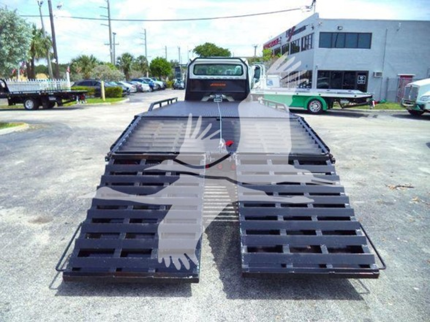Flatbed truck with foldable loading ramps in open yard, Freightliner Business Class M2 106 style bed visible.