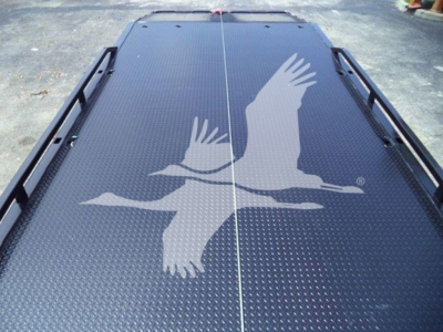 Flatbed truck bed with diamond plate surface and cutout rails; top view shows Freightliner branding on load bed with a white graphic of flying birds.