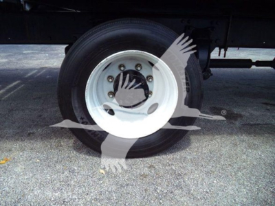 Freightliner Business Class M2 106 wheel and tire under flatbed, white steel rim with lug nuts visible.