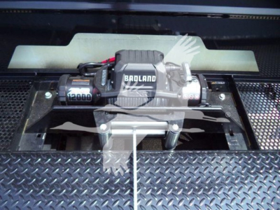 Winch mounted on diamond plate bed with Badland winch brand and 12000 label visible