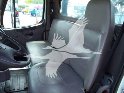 Truck cab interior of a 2012 Freightliner Business Class M2 106 showing two front seats and steering wheel; watermark of a bird graphic layered over image.