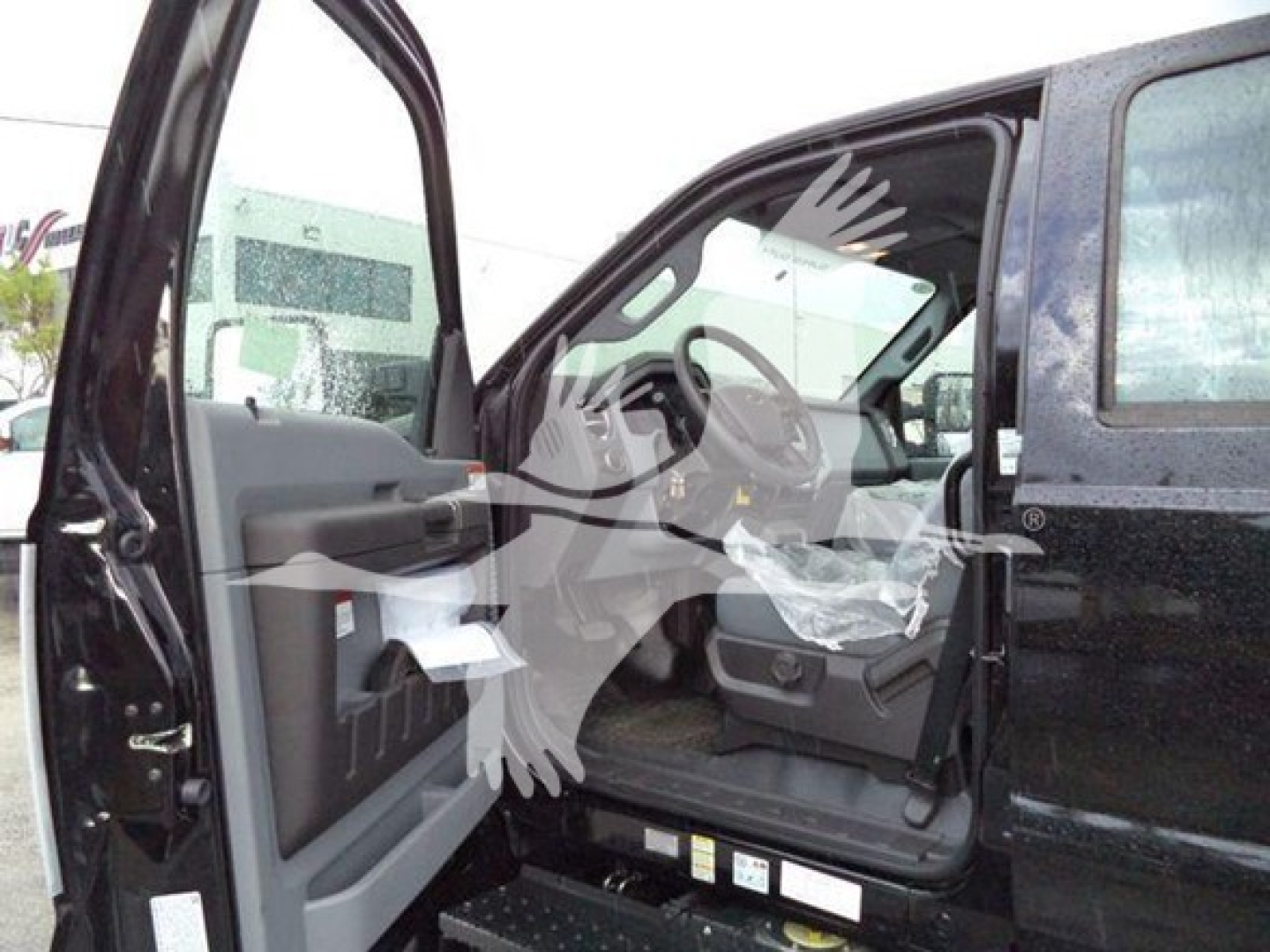 Ford F750 Rollback truck cab interior with driver’s door open showing steering wheel, dashboard, and seat area.