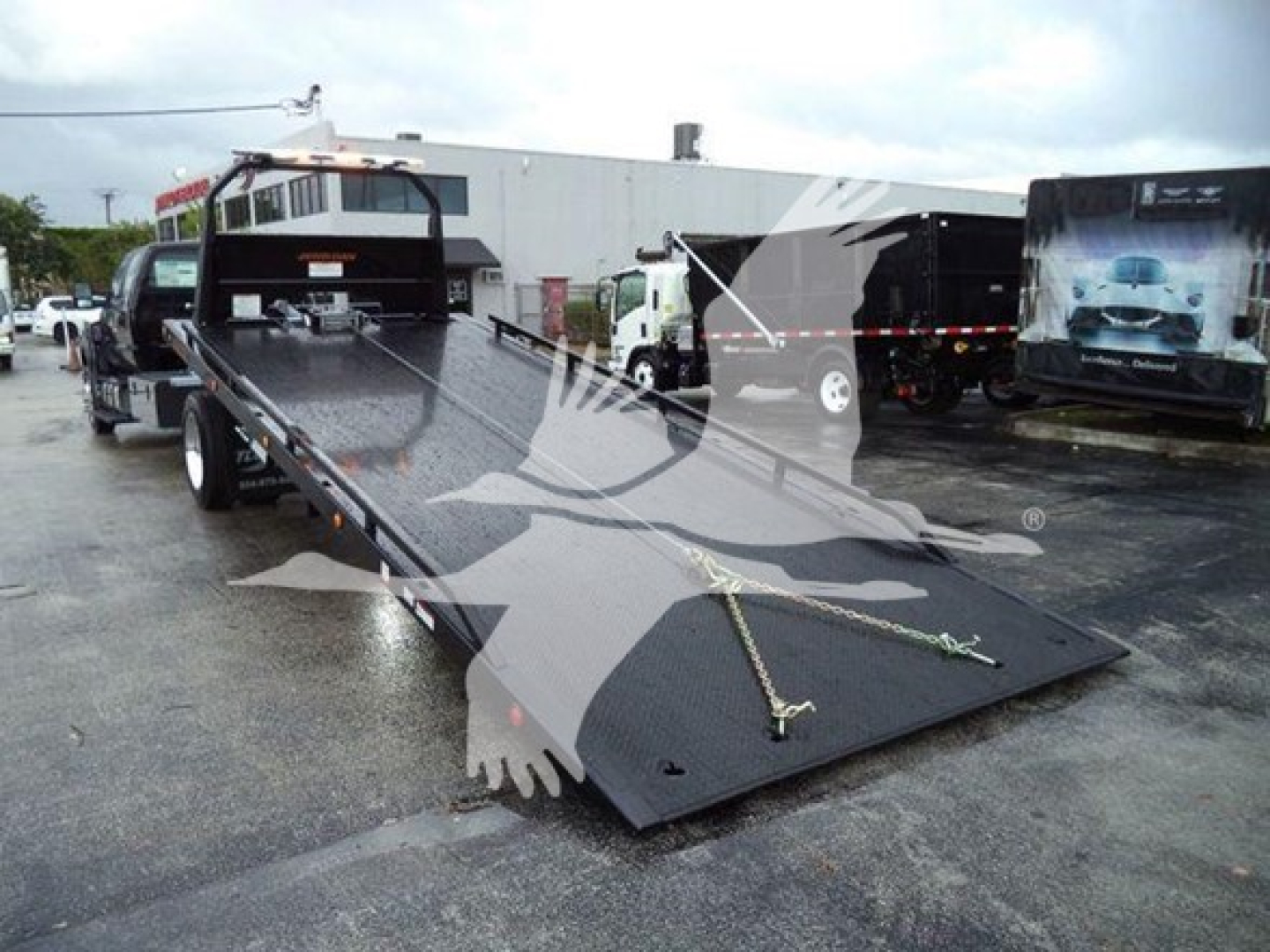 Ford F-750 rollback truck with a lowered flatbed in a dealership lot showing the equipment bed and front cab in view.