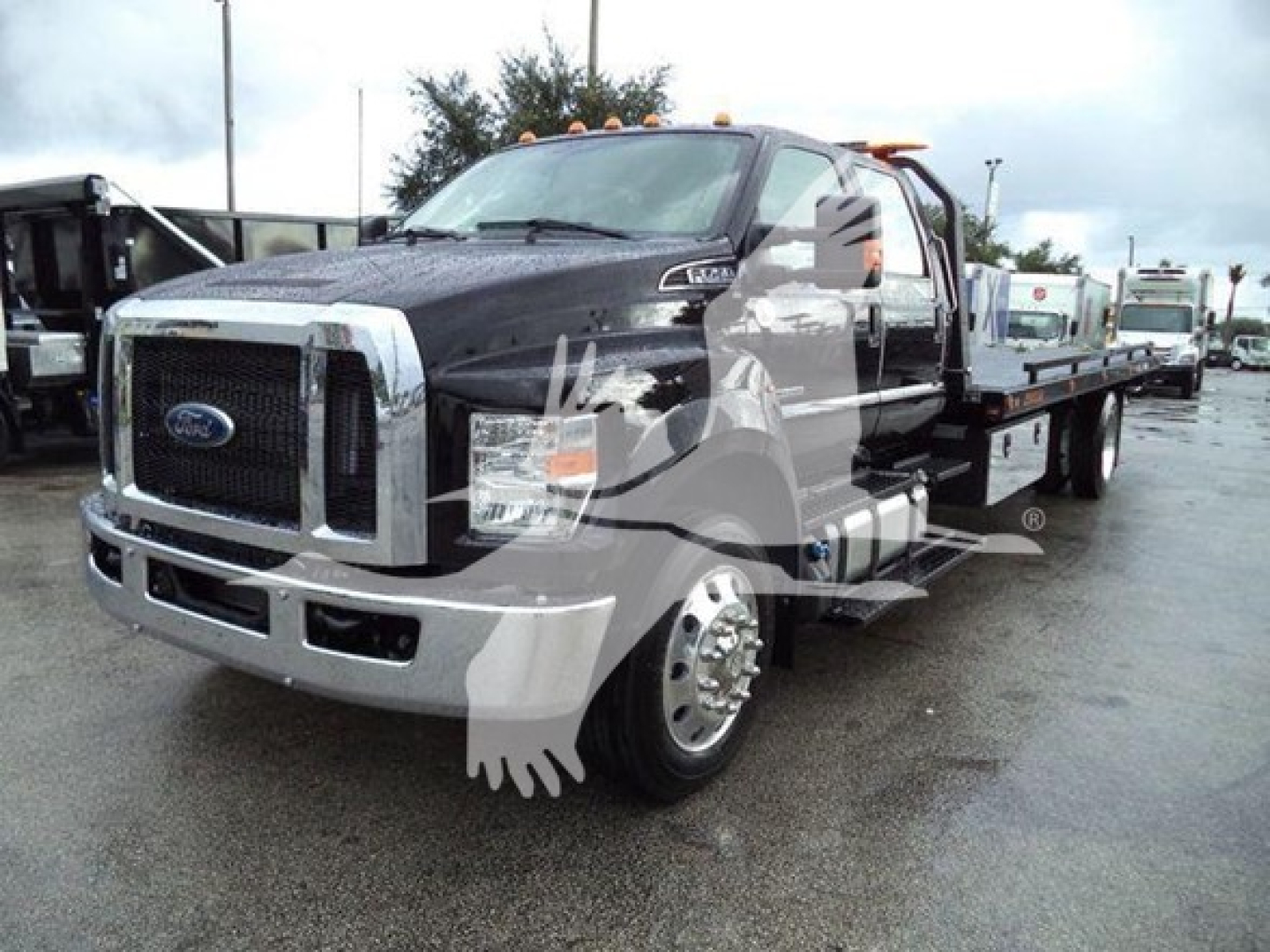Ford F-750 rollback truck with extended cab, chrome front bumper, and dual rear axles. Text on image: Ford logo on grille.