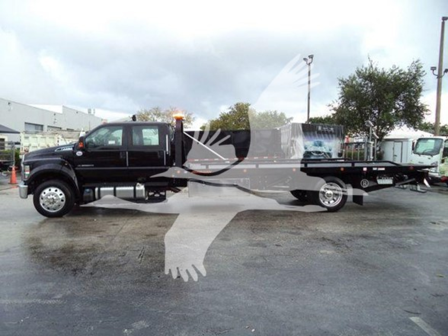 Ford F-750 rollback truck in side profile showing black cab and flatbed with towing equipment