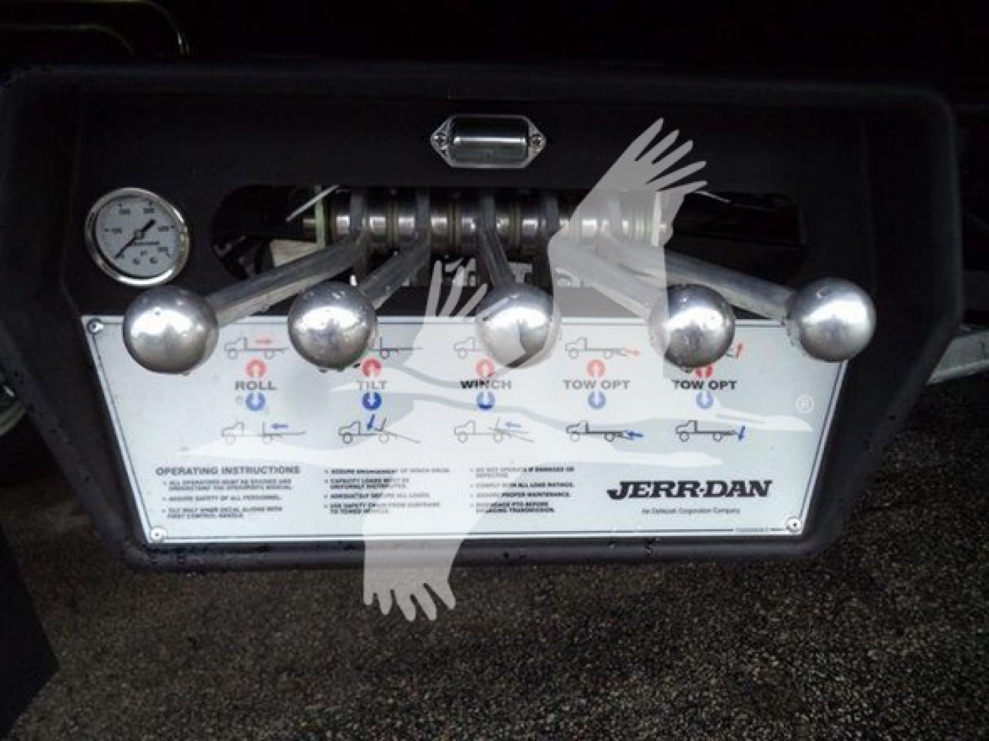 Jerr-Dan rollback tow truck control panel with multiple chrome levers and a pressure gauge visible.