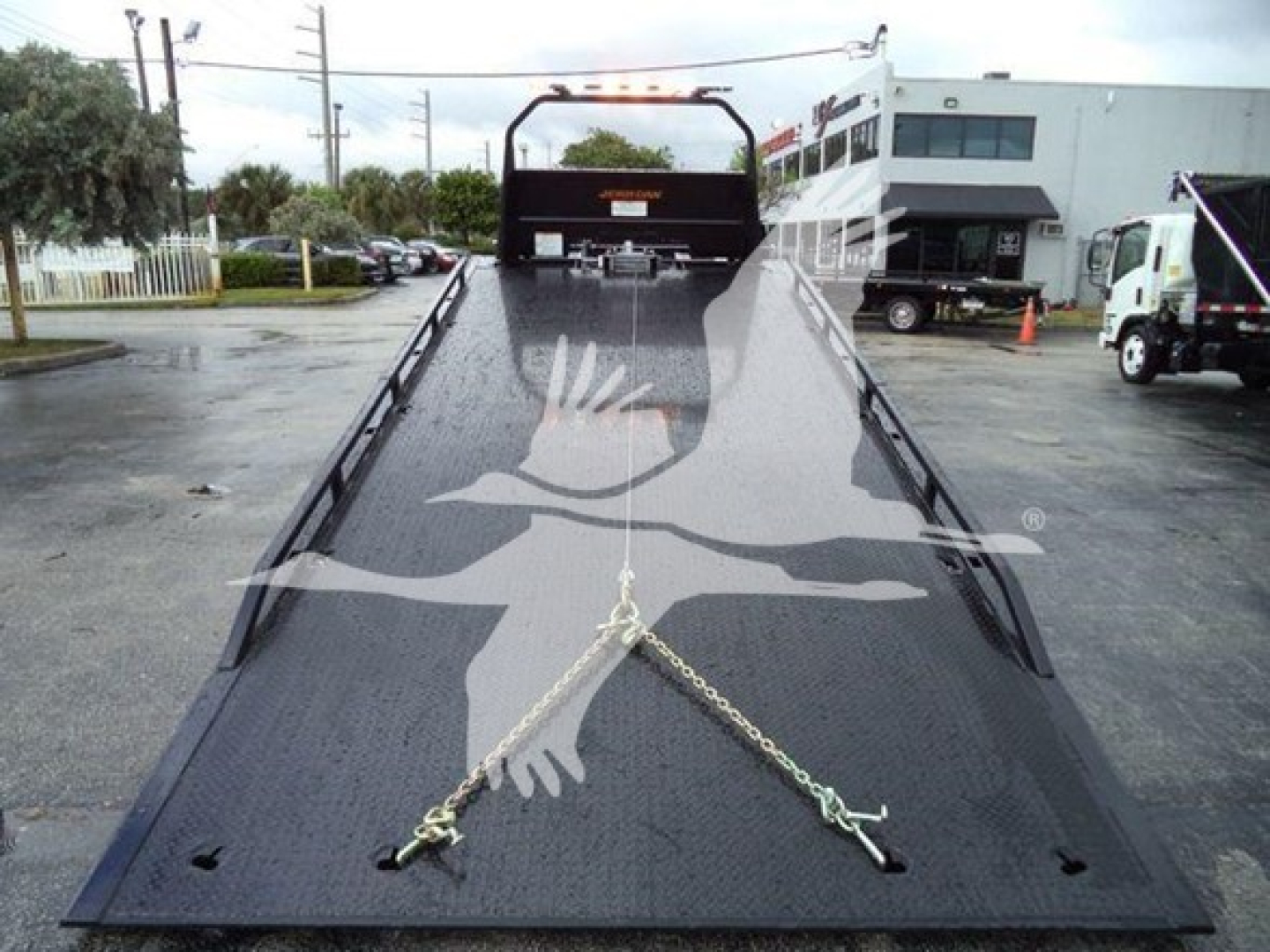 Ford F-750 Rollback truck flatbed with ramps and chain anchors in view.