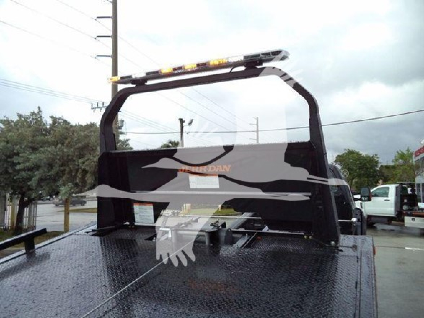 Ford F-750 rollback truck bed with a rear cab guard and a rooftop light bar. Text on the truck bed and rear window includes brand logo and faint markings.