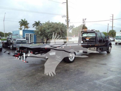 Ford F750 tow truck rollback bed with wheel lift and towing equipment visible, side view showing cab and flatbed.