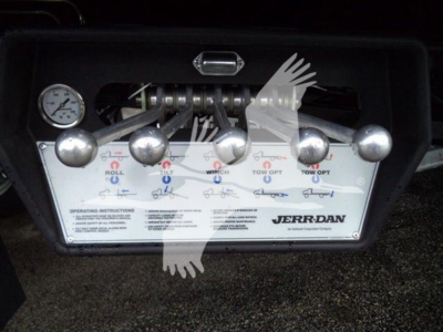 Jerr-Dan rollback tow truck control panel with multiple chrome levers and a pressure gauge visible.