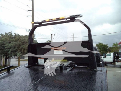 Ford F-750 rollback truck bed with a rear cab guard and a rooftop light bar. Text on the truck bed and rear window includes brand logo and faint markings.