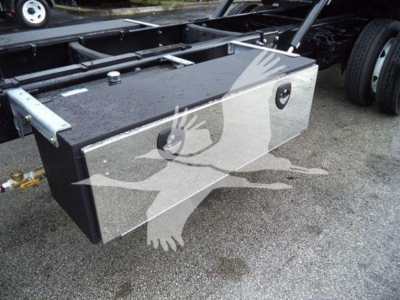 Flat rectangular metal toolbox mounted behind Ford F750 cab, with round lock and drainage port visible, on rollback truck chassis.