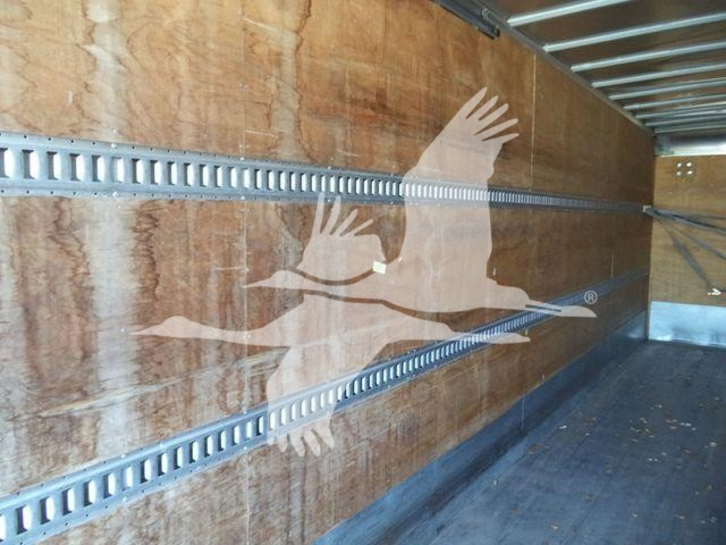 Truck cargo area of a 2019 International Durastar 4300 showing side rails and plywood walls inside a box truck.