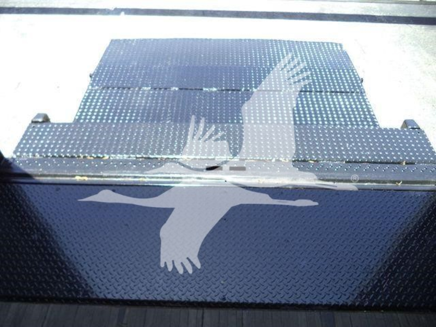 Toolbox or storage container with diamond plate pattern and a white silhouette of a bird in flight on the side.