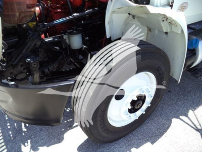 Truck engine bay and front wheel of a 2019 International Durastar 4300 box truck showing front tire and engine components.