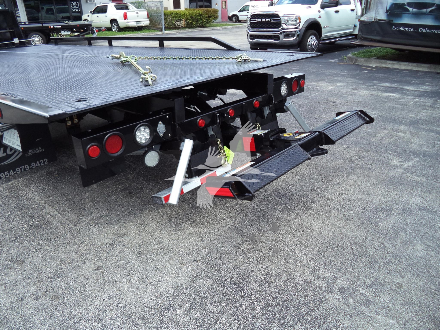 Flatbed tow truck equipment showing rear of rollback bed with hydraulic ramps and taillights.