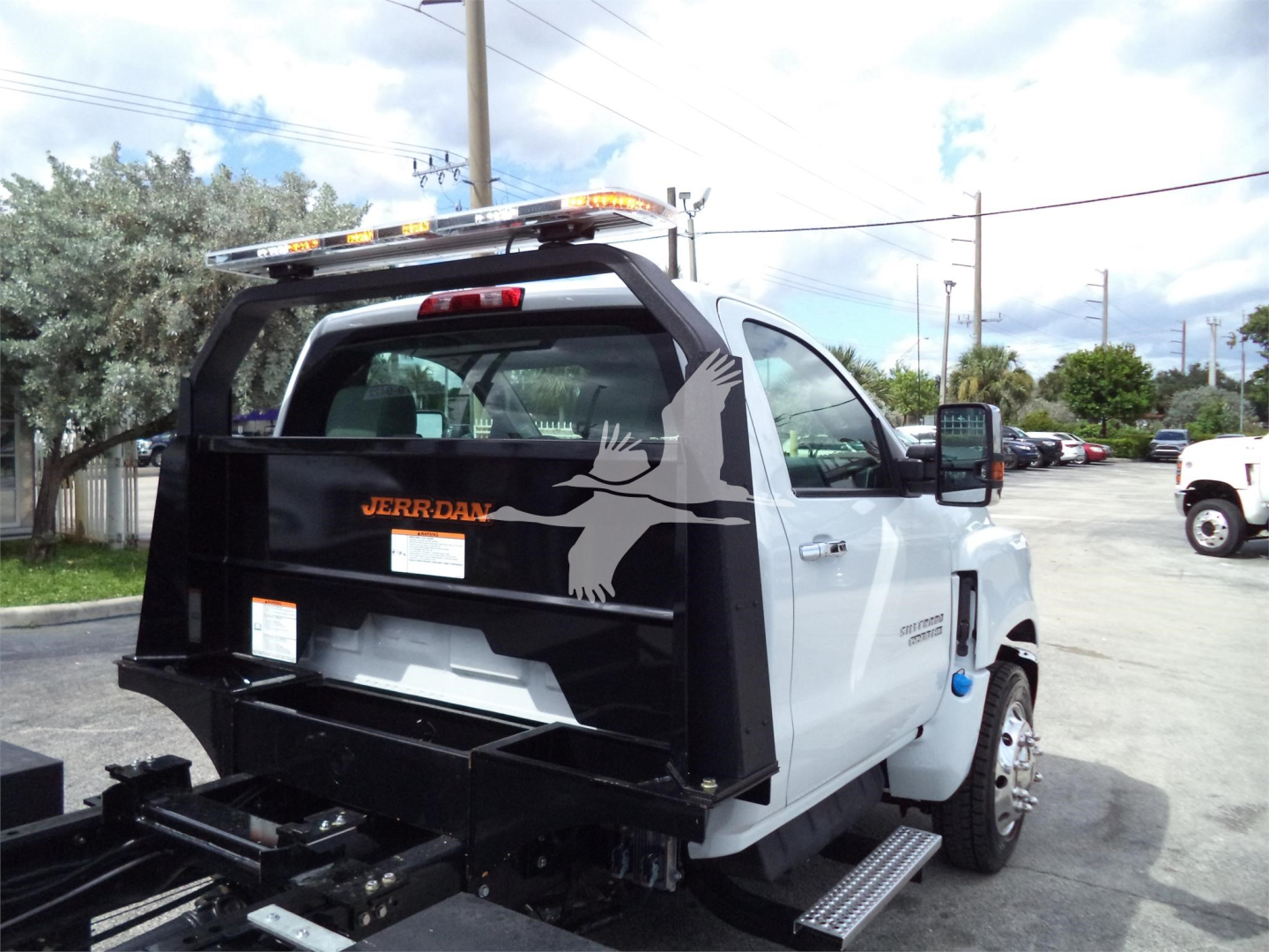 Truck: Chevrolet Silverado 6500HD rollback body side rear with Jerr-Dan equipment, rear view showing black equipment bed and bird decal on cab window.