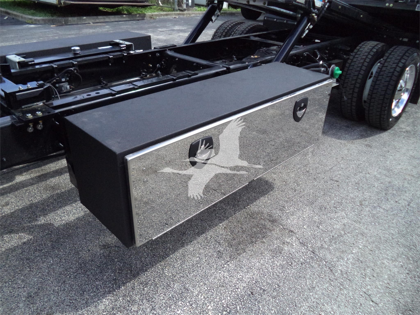 Truck bed toolbox mounted behind cab with reflective chrome finish and latch handles in a Silverado 6500HD chassis.