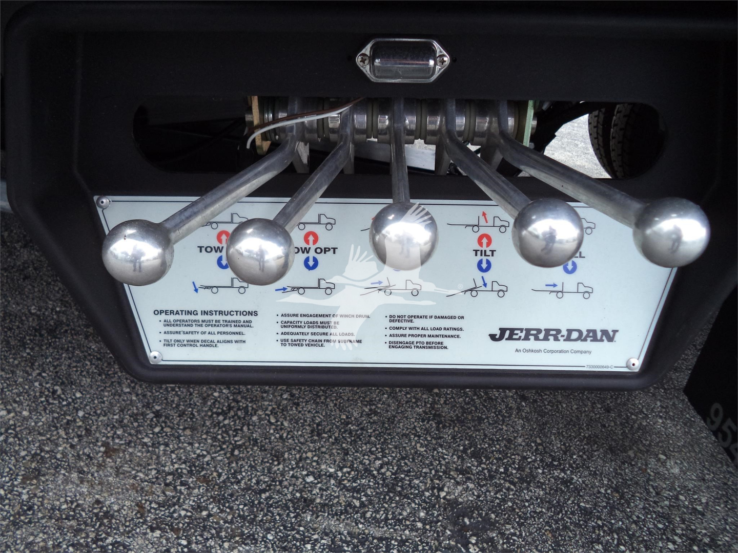 Trailer hitch control panel with levers and a JERR-DAN label on a rollback tow truck, showing multiple levers for tilting and lifting operations.