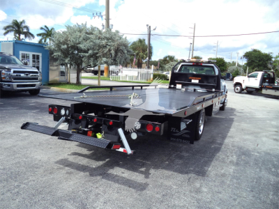 Flatbed tow truck with extended ramp and rear dual loading ramps visible in a lot, Silverado 6500HD listing image.