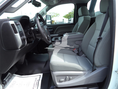 Truck interior showing front seats and dashboard of a 2023 Chevrolet Silverado 6500HD rollback truck with light gray cloth seats and steering wheel