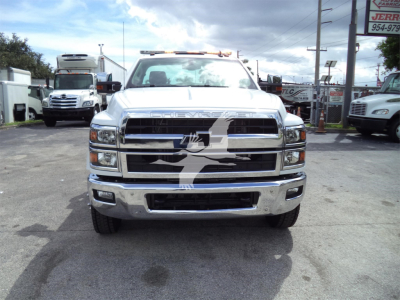 Front view of a white 2023 Chevrolet Silverado 6500HD rollback truck showing chrome grille and bumper.