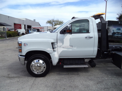 White Chevrolet Silverado 6500HD rollback truck side view showing cab, front wheel, side step, and rollback bed.