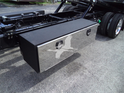 Truck bed toolbox mounted behind cab with reflective chrome finish and latch handles in a Silverado 6500HD chassis.