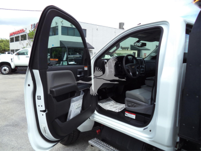 Truck cab interior open door showing dashboard and driver seat with papers on floor and exterior white body panels.