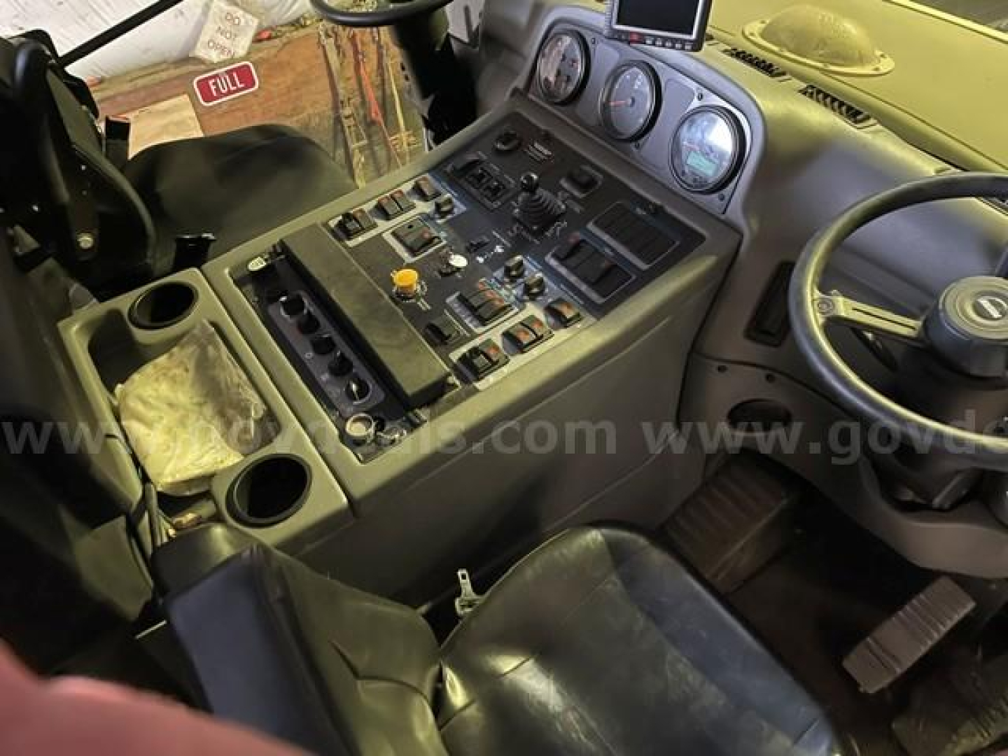 Cab interior of a 2021 Elgin Pelican sweeper showing dashboard with gauges, switches, and steering wheel.