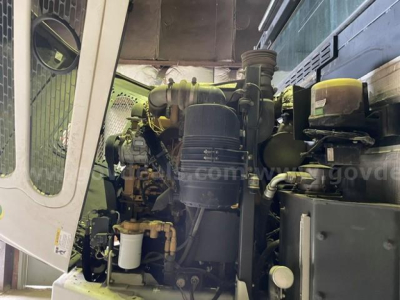 Front view of Elgin Pelican sweeper engine bay showing diesel engine, air filter, hoses, and coolant reservoir label text not fully legible.