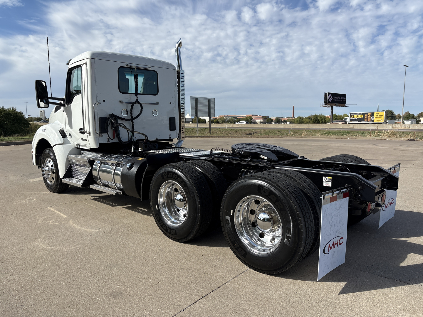 Kenworth T880 chassis cab tractor showing rear dual axle and fifth wheel missing, side view, white cab, chrome wheels.