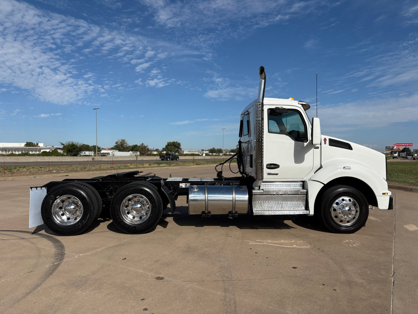 Kenworth T880 cab and chassis side profile showing white tractor with chrome fuel tanks and three rear axles. No visible text on the truck.