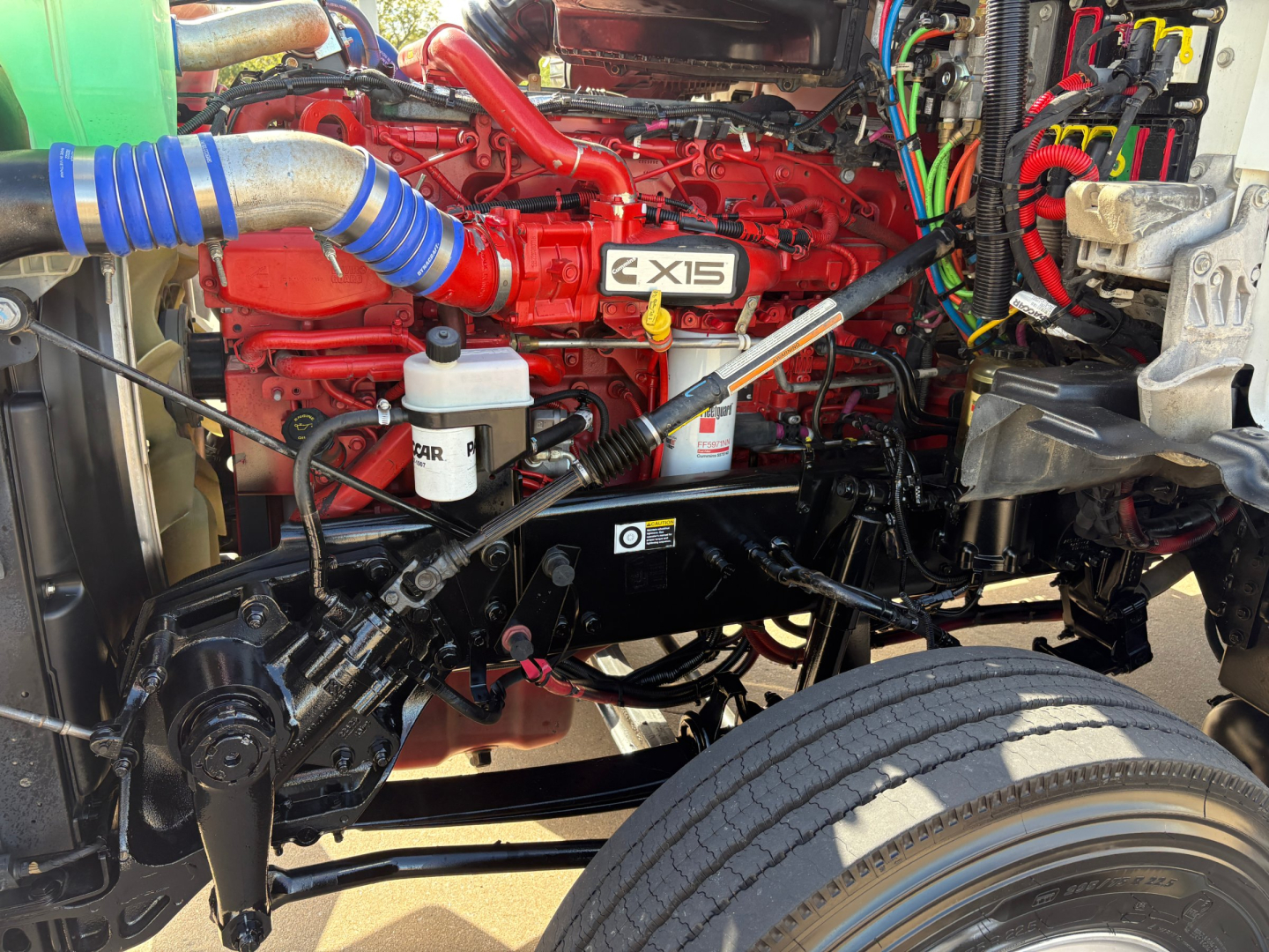 Kenworth T880 engine bay showing X15 engine and various hoses and wiring harnesses.