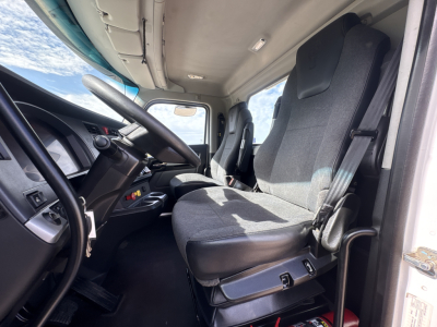 Kenworth T880 cab interior showing driver seat and steering wheel with gray fabric seat, dashboard controls, and door frame.
